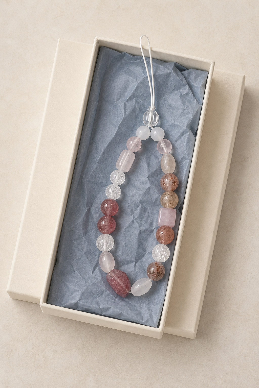 ASTRÉ berry phone chain presented in an ivory keepsake box
